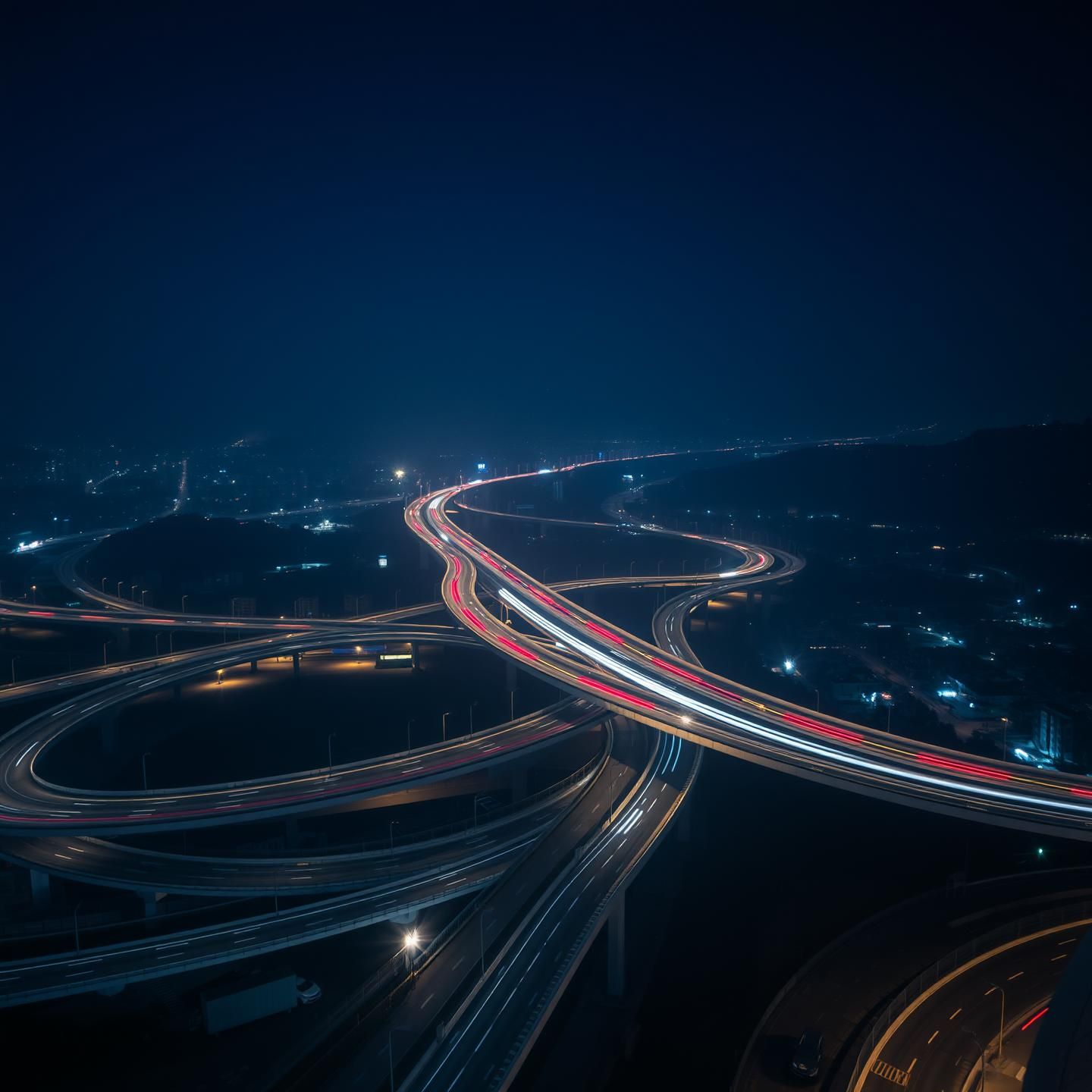 Serene Blue Hour Cityscape: Glowing Light Trails Weave Through Urban Darkness
 | Unfold Lens